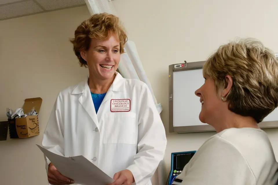Médica sonriente hablando con una paciente en la consulta