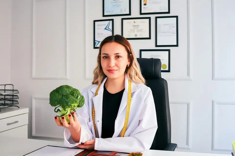 Dietista-nutricionista en su consulta con fruta y verdura sobre la mesa